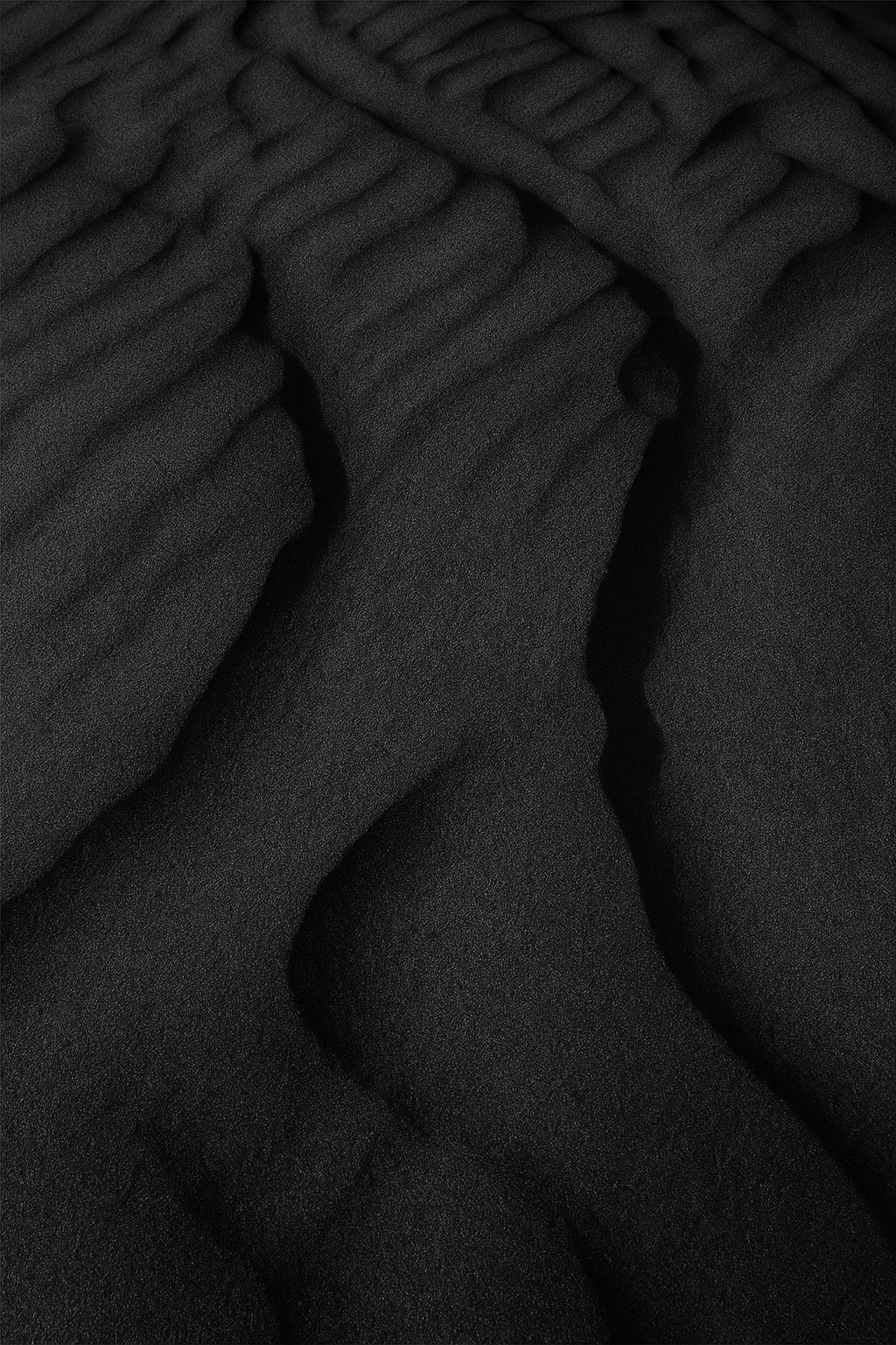 Aesthetic backdrop of fine black sand highlighting the volcanic inspiration behind the product., vmen&