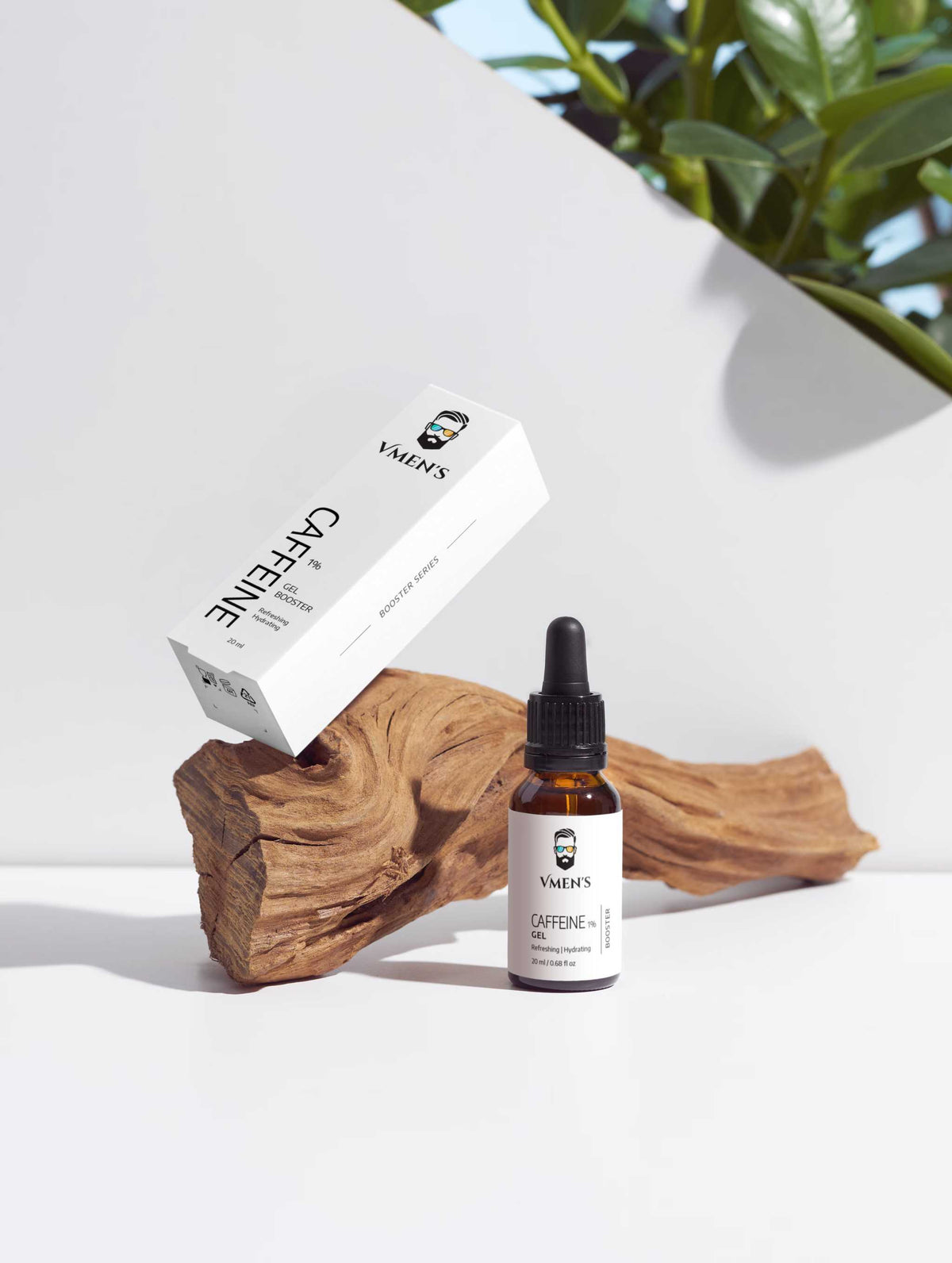 VMEN’S Caffeine Eye & Face Gel Booster for Men with its white carton beside driftwood and green leaves.