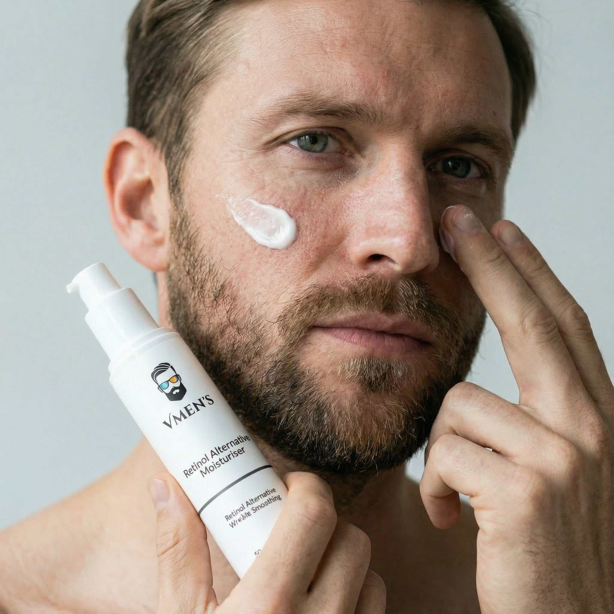 Man applying moisturizer to his face with a bottle labeled &