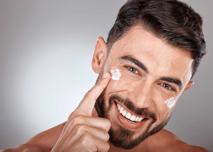 Cheerful man applying anti-age day cream, demonstrating a radiant, youthful complexion and effective men’s skincare.