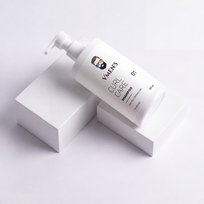 VMEN’S Curly Hair Shampoo for Men in a white pump bottle resting diagonally across white display blocks.
