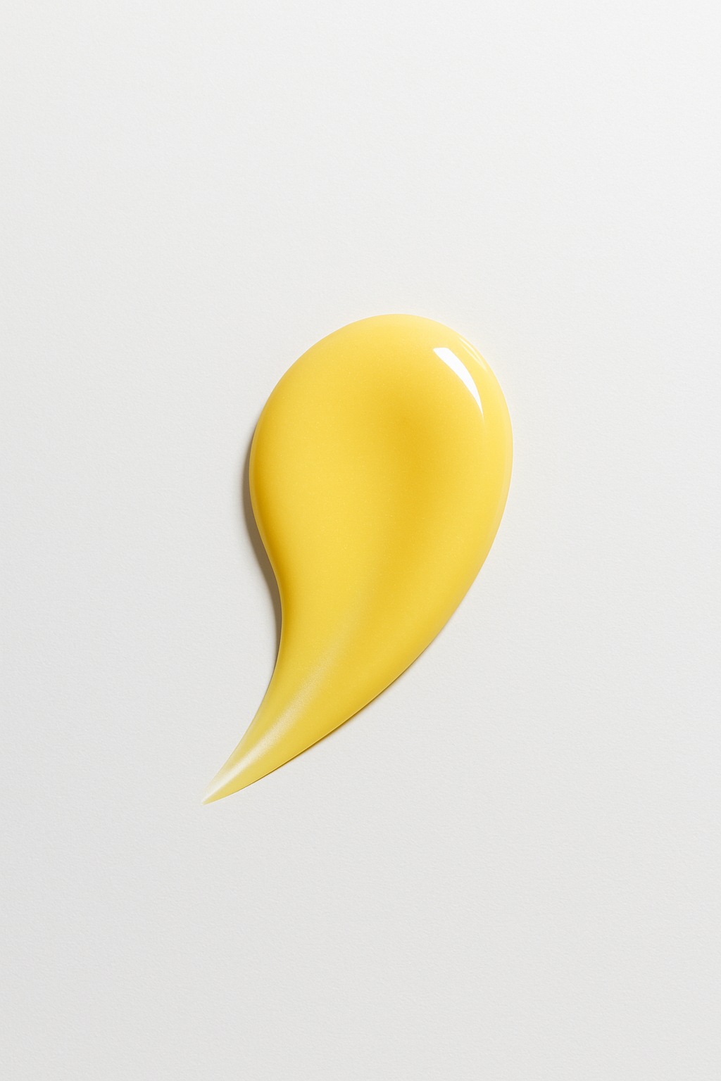 A glossy yellow teardrop of Vitamin C serum on a clean, light gray background, showcasing its smooth, rich texture and radiant finish.