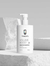VMEN’S Keratin Volume Boost Shampoo white pump bottle displayed among white stone blocks.