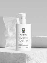 VMEN’S Sensitive Scalp Shampoo white pump bottle displayed among white stone blocks.