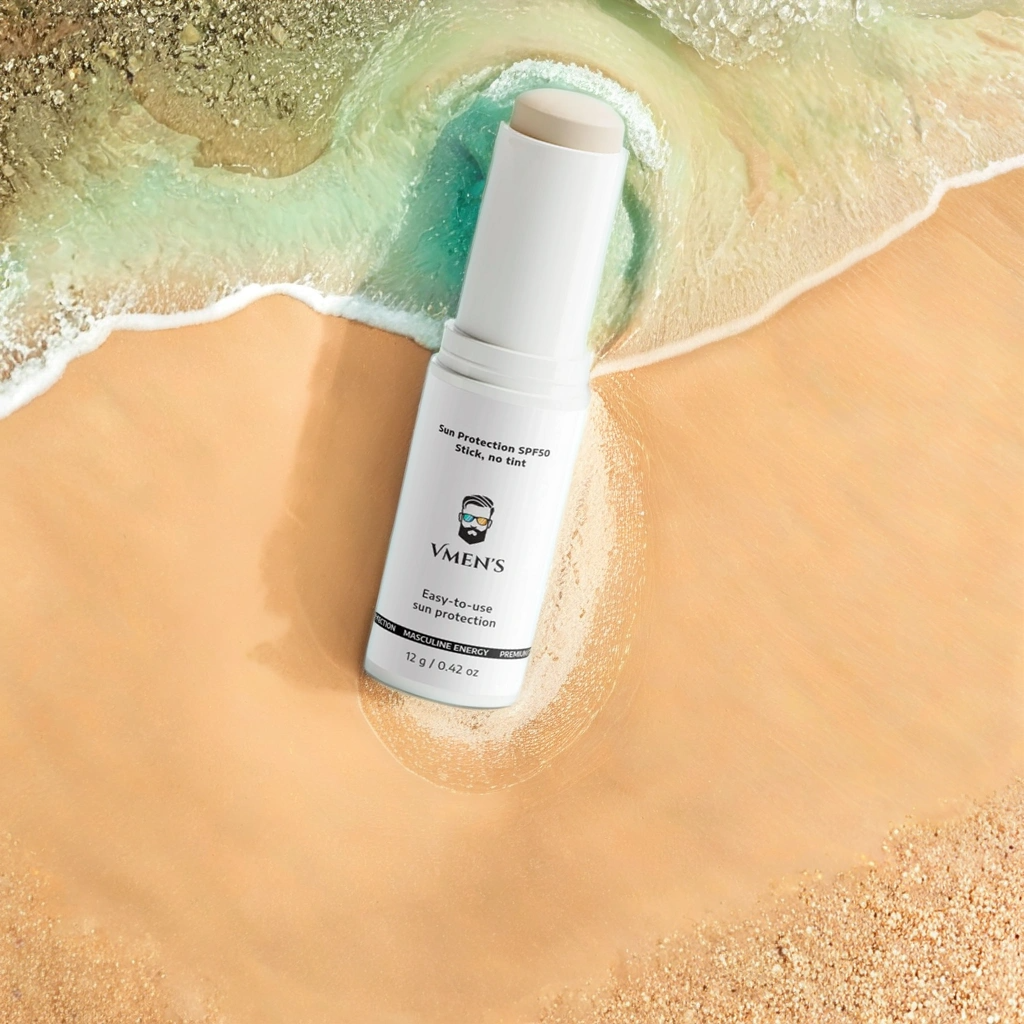 VMEN’s SPF50 Stick without tint lying on wet sand – invisible mineral sunscreen for men, water-resistant and reef-safe.