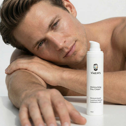 Man lying on a white surface with a bottle of VMEN&