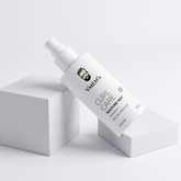 VMEN’S Anti-Frizz Curly Hair Texture Mist for Men spray bottle resting diagonally across white display blocks.