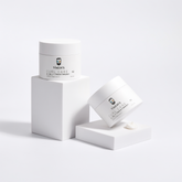 Two VMEN’S 3-in-1 Curly Hair Treatment for Men jars on white display blocks beside a small cream swatch.