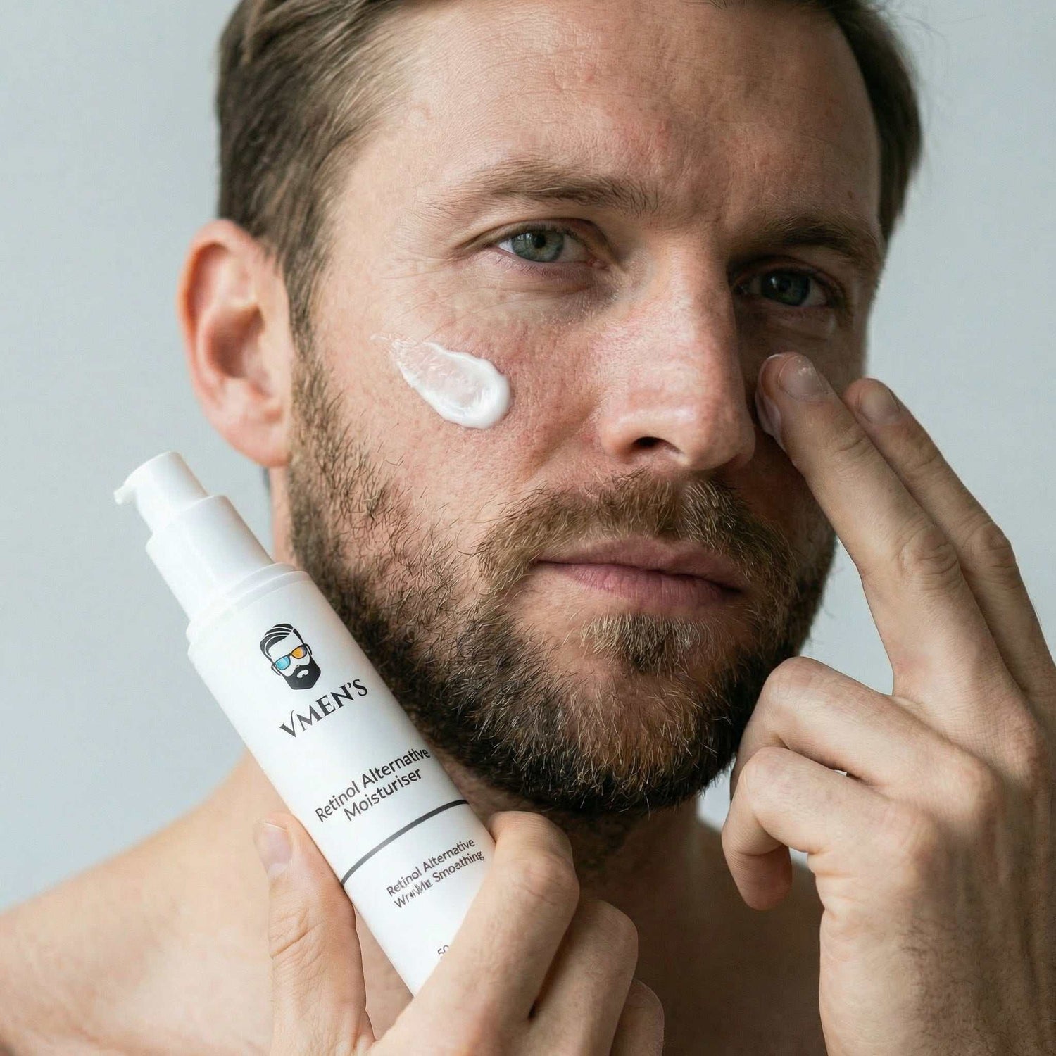 Man applying moisturizer to his face with a bottle labeled &