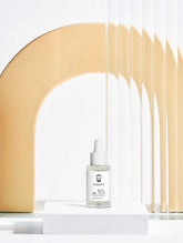 VMEN’S 10% Lactic Acid Peel dropper bottle on a white plinth beneath a golden arch.
