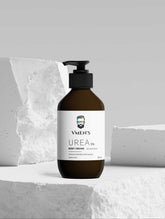 VMEN’S Urea Body Cream brown pump bottle displayed among white stone blocks.